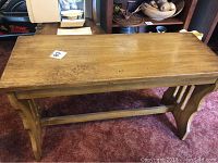 Top down angle showing the rectangular wooden seat with natural wood finish and minor surface wear.