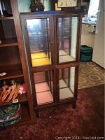 Photo of two stacked wooden display shelves with glass doors; shelves closed showing wooden frame and glass panels.