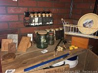 Photo showing glass jars with wooden lids, metal spice rack with salt and pepper shakers, vintage cooking mold plates, wooden utensils, white metal wire basket and decorative plate.