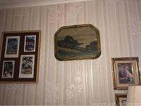 Wall with four framed prints grouped together, elongated framed landscape painting, and small portrait painting on wallpapered wall