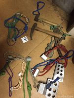 Full view of climbing gear including harnesses, ropes, pitons, and hammer on floor.