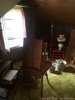 Wooden travel easel set up in room with additional chairs and lamps around