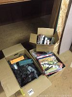 Boxes on floor containing various model train kit parts including tracks, train cars, and accessories