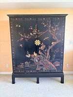 Front view of closed armoire showing painted design and hardware
