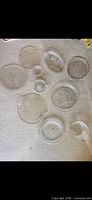 Group of clear pressed glass plates and bowls arranged on floor