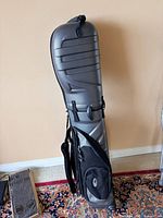 Hard-shell rolling golf travel bag, side view showing pockets, straps, wheels