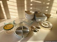 Full group of ceramic bowls, plates, ramekins, glass bowls, glass containers with lids, and divided serving tray