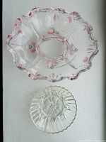 Top-down view of both pressed glass bowls showing size difference, patterns, and pink accents on larger bowl