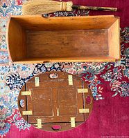 Rectangular wooden bassinet, round tray underside, and whisk broom displayed together