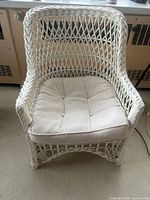 Front view of white wicker armchair with cushion