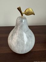 Front view of marble pear sculpture showing gold-tone leaf and veined marble body