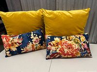 Set showing two yellow velvet square pillows and two navy floral lumbar pillows