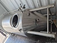 Overall view of stainless conical tank on its side in container