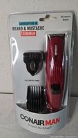 Front view of sealed Conair MAN corded beard & mustache trimmer package showing trimmer and comb attachments