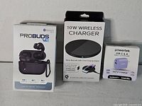 Front view of all three retail boxes: ProBuds V2 earbuds, 10W wireless charger, Powertek wall charger
