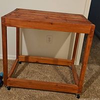 Full front view of stained wood TV stand showing slatted top and casters