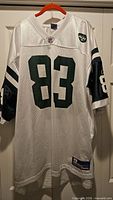 Front view of white New York Jets #83 jersey on hanger