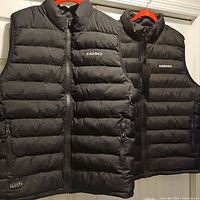 Front view of both Kodoku heated vests hanging