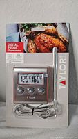 Front of sealed package showing Taylor digital probe thermometer, stainless probe and braided cord