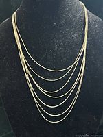 Full necklace on display bust showing seven draped gold-tone chains