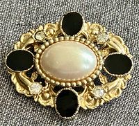 Front view showing faux pearl, black cabochons, rhinestones and gold-tone frame