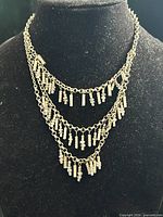 Full view of necklace on bust showing three chains with fringe