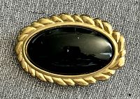 Front view of Monet brooch showing gold tone rope border and black cabochon