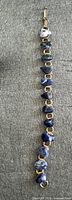 Full view of bracelet showing gold-tone links and blue stones