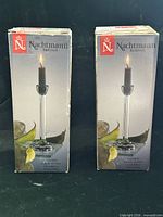 Two boxed Nachtmann candlesticks showing brand and product image