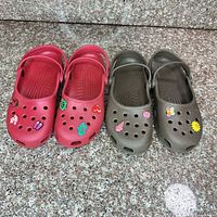 Top view of both red and brown-olive Crocs showing color, size, charms, and heel straps