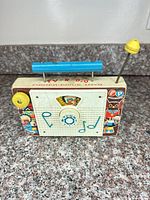 Front view of Fisher-Price TV-R-Dio toy radio showing dial, graphics, handle and antenna