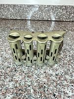 Front view of four-tube brass coin dispenser showing slotted barrels and thumb levers