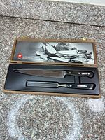 Open wooden case showing carving knife and fork inside fitted tray
