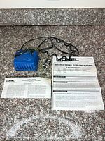Overall view of blue transformer controller, lockon connector and two Lionel paperwork sheets