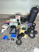 Overall view of lens, flash, filters, caps, tripod and accessories on countertop