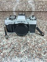Front view of Minolta XG-M body with body cap and strap ends visible