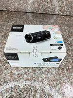 Front and side of sealed Sony HDR-CX220 camcorder box