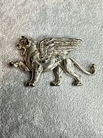 Front view of silver-plated winged lion brooch