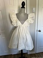 Front view of white ruffled mini dress on mannequin