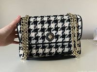 Front view of houndstooth shoulder bag with gold chain straps and turn-lock