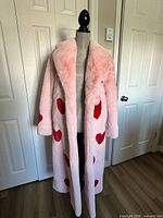 Front view of pink faux fur coat with red hearts on mannequin