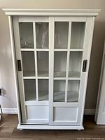 Front view of white cabinet with glass sliding doors