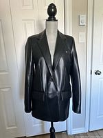 Front view of black faux leather blazer on dress form