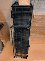 Stack of black wire shelf panels leaning against wall