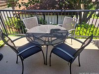 Round Kettler mesh patio table with four matching armchairs on balcony