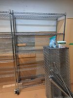 Assembled chrome shelving rack with extra shelves leaning beside it