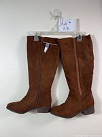 Full pair of brown knee-high boots on hanger