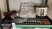 Shelf view showing all items: hand blender box, slow cooker, wooden bowls, glass bowl, carving set
