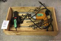 Tray containing corded drill, cordless screwdriver in charging dock, cords, and auger bits