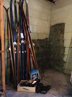 Multiple pairs Fischer Trak skis with bindings and poles leaning against wall